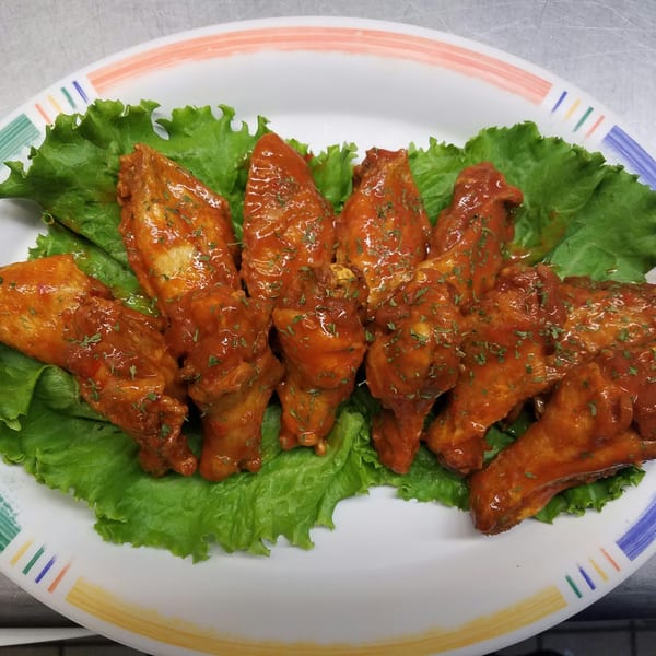 A plate of Hen House Cafe's chicken wings, coated in a rich red sauce and garnished with parsley.