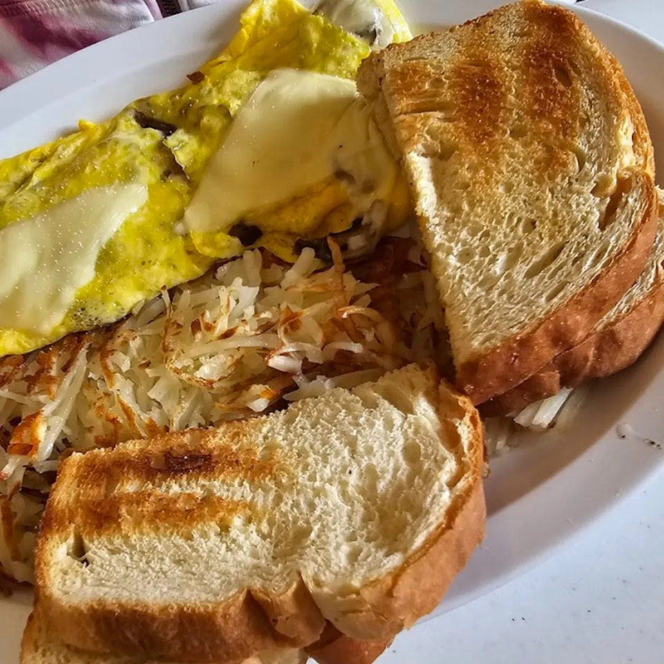 A breakfast plate with a cheesy omelet, hash browns, and two slices of toasted bread.
